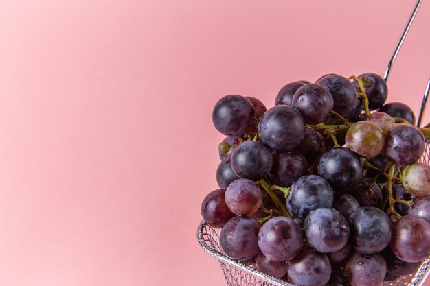 Front view of fresh sour grapes inside fryer on pink wall