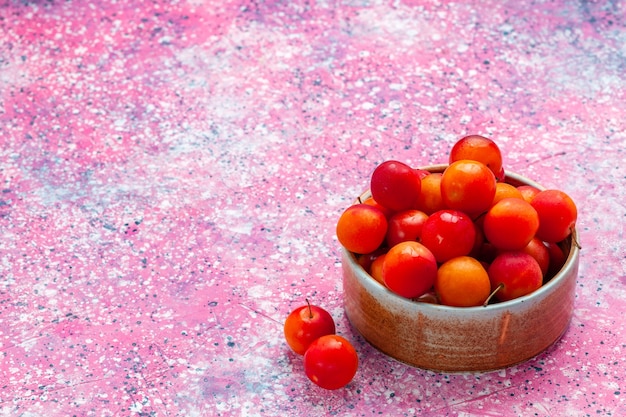 正面図淡いピンクの机の上の小さなプレートの中に新鮮な酸っぱいプラムのまろやかな果物。