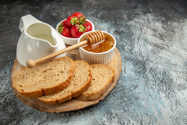 Front view fresh strawberries with bread and honey on dark surface fruit sweet jelly