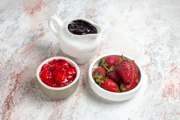 Fragole fresche di vista frontale con marmellata su uno spazio bianco