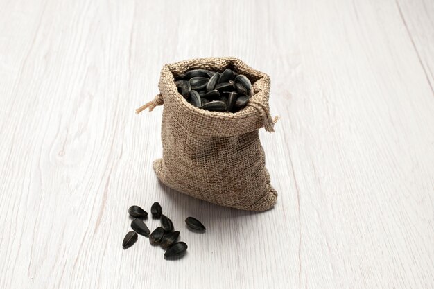 Front view fresh sunflower seeds black colored seeds inside little bag on white background seed snack photo many oil