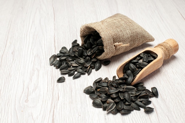Front view fresh sunflower seeds black seeds on white desk many seed oil plant bag