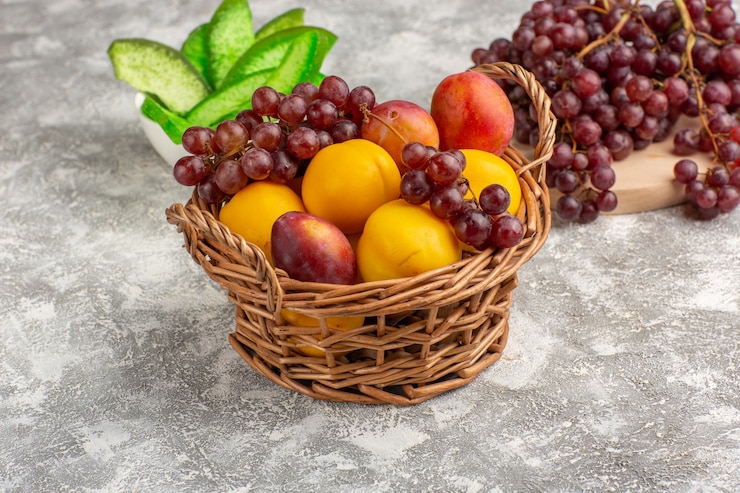 Free Photo front view fresh sweet apricots with plums inside basket along with grapes on white desk