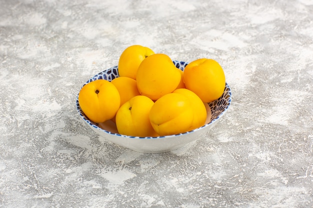 Front view fresh sweet apricots yellow fruits inside plate on white surface