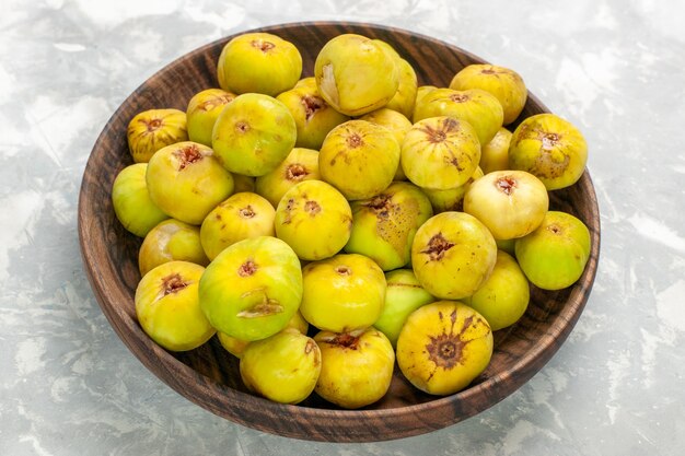 Front view fresh sweet figs inside brown plate on light desk