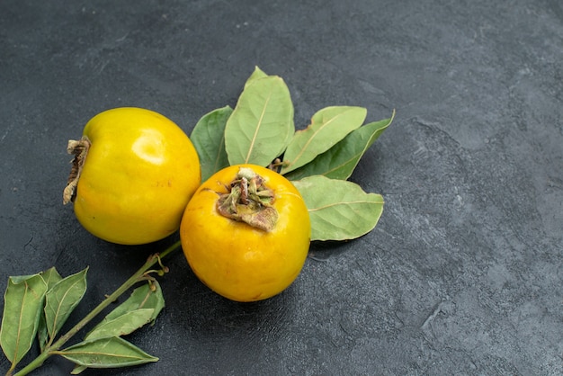 無料写真 暗い背景に葉を持つ新鮮な甘い柿の正面図