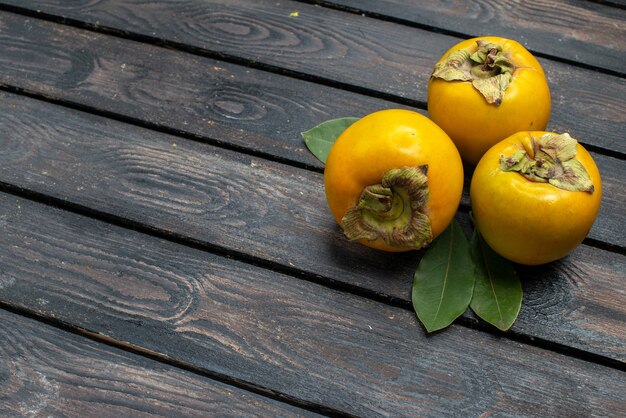 Свежая сладкая хурма на деревянном деревенском столе, вид спереди, спелые спелые фрукты