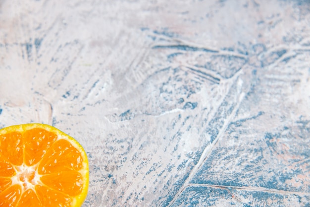 Свежий ломтик мандарина на голубом столе цитрусовых, вид спереди