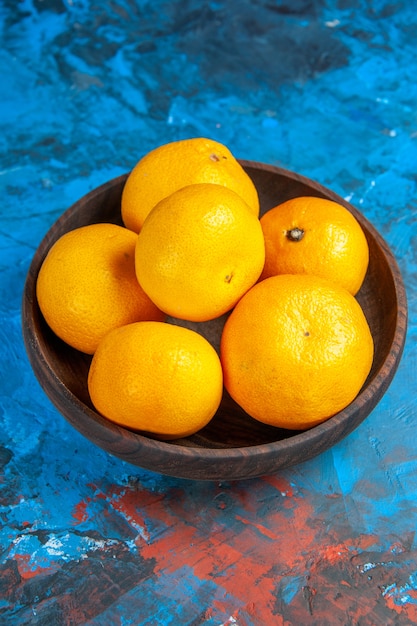Вид спереди свежие мандарины внутри тарелки на синем столе фруктовое дерево цветное фото сок цитрусовые