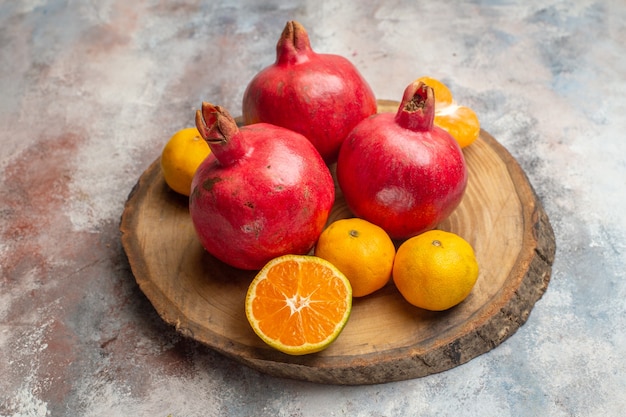 Front view fresh tangerines with red pomegranates on light background photo exotic juice vitamine taste fruit tree color