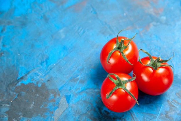 Pomodori freschi di vista frontale sul tavolo blu