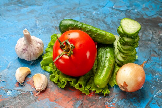 Вид спереди свежие овощи огурцы, помидоры, зеленый салат и чеснок на синем фоне, еда, салат, здоровая, спелая пища, диета, цвет
