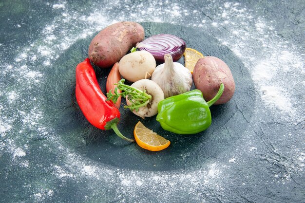 Вид спереди свежие овощи, чеснок, перец, лук и картофель на темно-синем спелом салате, пищевое растение, овощная мука