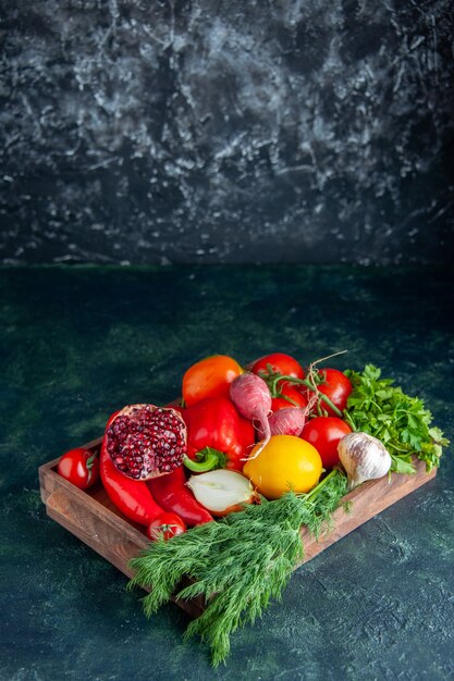 Front view fresh vegetables and half pomegranate on wood board on dark with free space