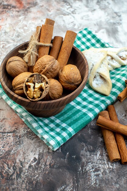 Свежие грецкие орехи с корицей и сладкой выпечкой на светлой поверхности, вид спереди