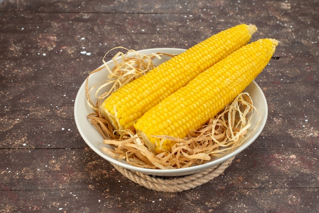 Front view fresh yellow corns inside white plate on wood, food meal raw color