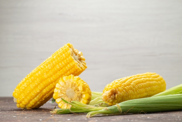 Front view fresh yellow corns with peels on grey, food meal color