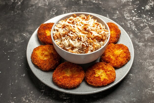 Front view fried cutlets with cooked rice on dark surface dish rissole meat