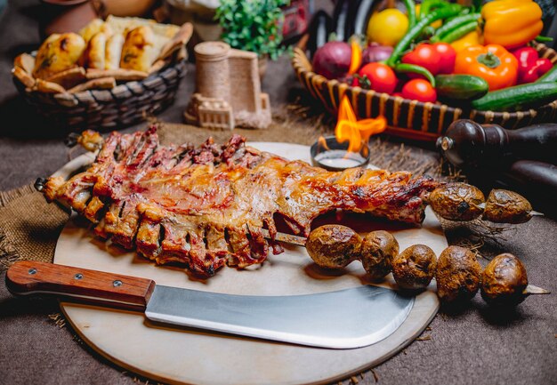 Front view fried lamb ribs in a tandoor on skewers with baked potatoes