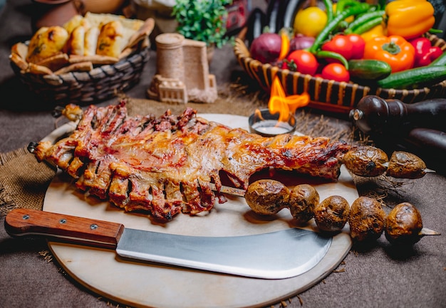 Front view fried lamb ribs in a tandoor on skewers with baked potatoes