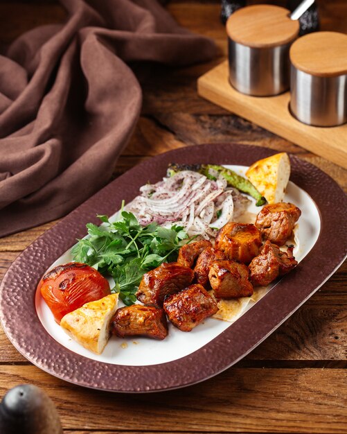 A front view fried meat with greens inside plate on the brown wooden desk food meal meat vegetable