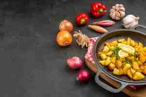 Бесплатное фото Вид спереди жареный картофель внутри сковороды со свежими овощами на темном столе