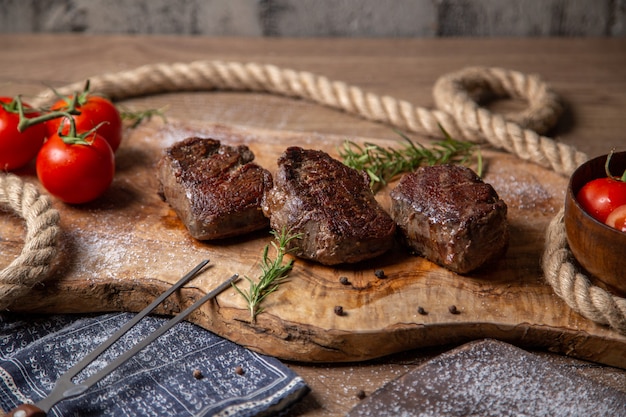 正面の木製の机の上の新鮮な赤いトマトと緑のおいしい肉の揚げ