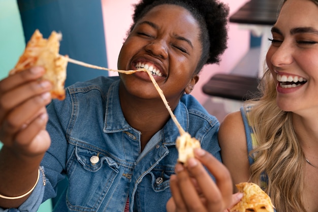 Foto gratuita amici di vista frontale che mangiano in un modo divertente