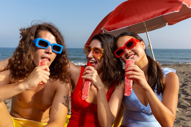 Front view friends eating ice cream on beach