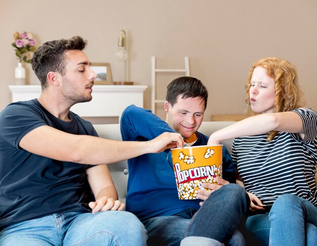 Front view of friends eating popcorn at home