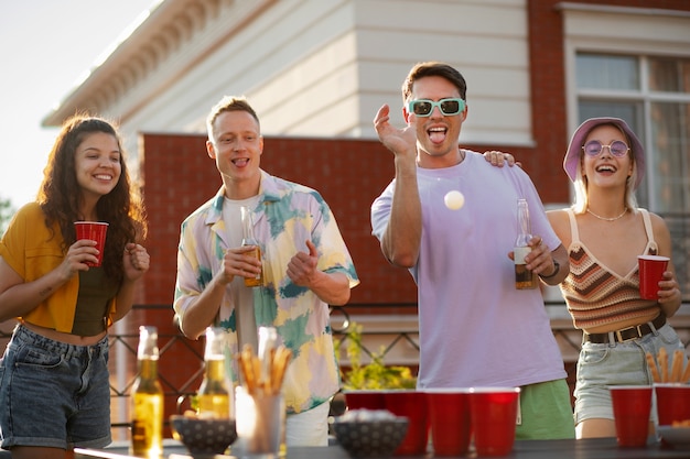 Front view friends playing beer pong