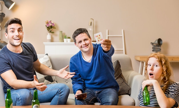 Front view of friends playing cards at home and having beer