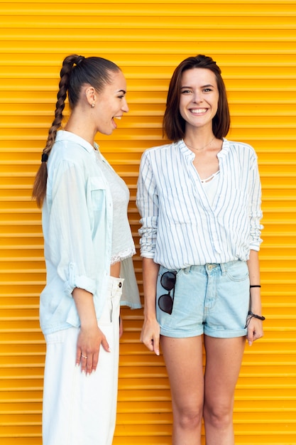 Free photo front view friends smiling with yellow background