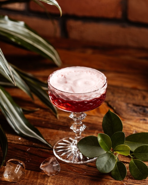 Foto gratuita un cocktail di frutta vista frontale con ghiaccio sul succo di bevanda cocktail scrivania in legno marrone