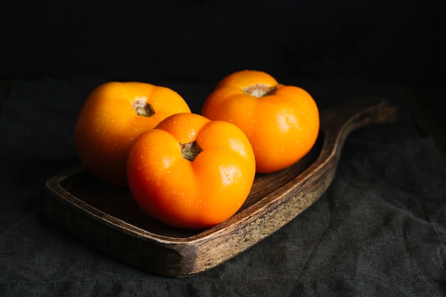 Front view of full grown orange tomatoes on cutting board
