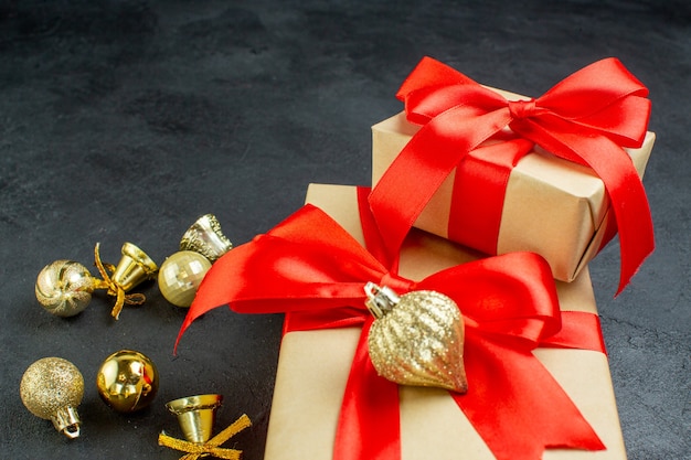 Front view of gift box with red ribbon and decoration accessories on dark background