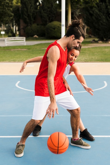 Front view of girl and boy playing basket