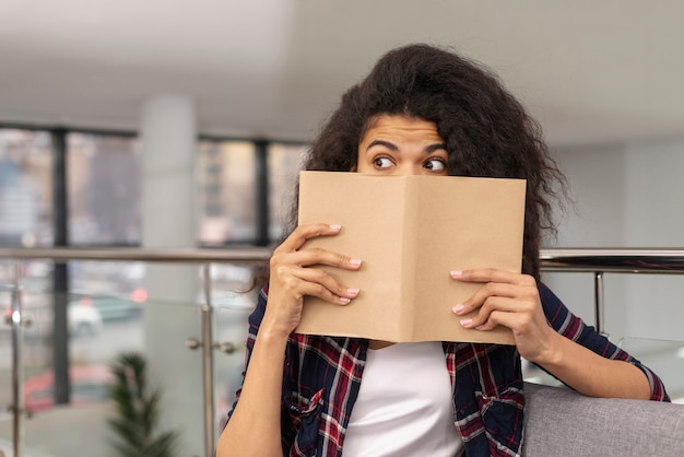 Free photo front view girl covering her face with book