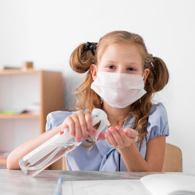 Front view girl disinfecting in class