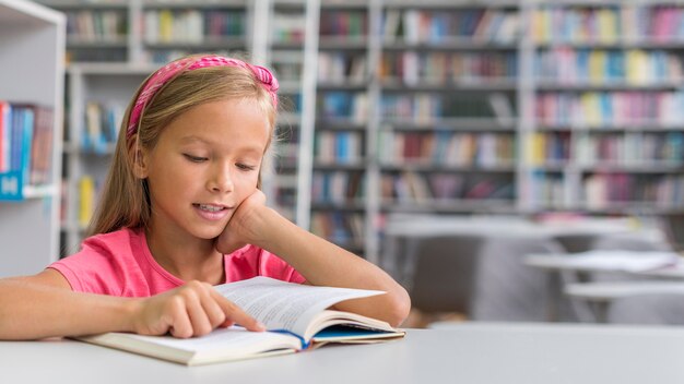 Девушка вид спереди делает свою домашнюю работу в библиотеке с копией пространства