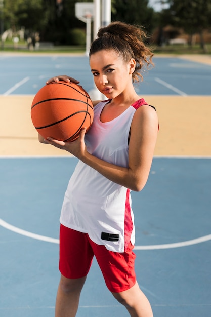 Vista frontale della palla di pallacanestro della tenuta della ragazza