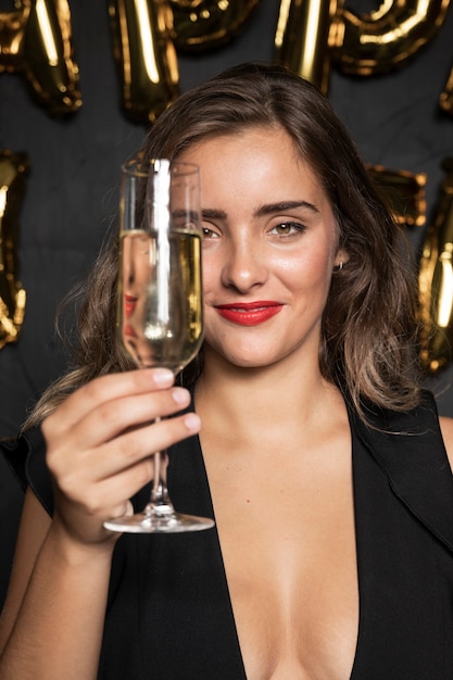 Ragazza di vista frontale che tiene un bicchiere di champagne