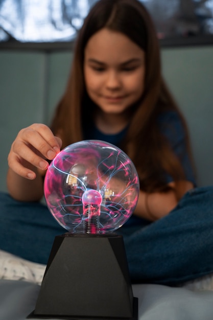 Free photo front view girl interacting with a plasma ball