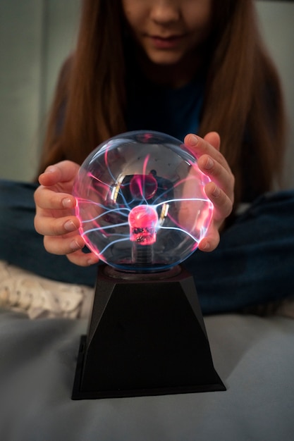 Free photo front view girl interacting with a plasma ball