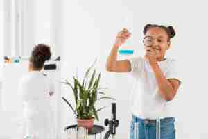 Free photo front view of girl looking at potion with magnifying glass