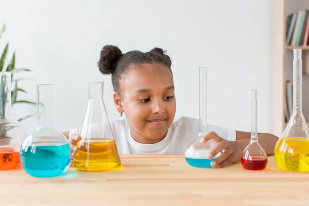 Front view of girl looking at test tubes with potions