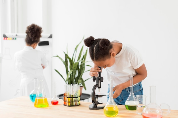 Front view of girl looking through microscope