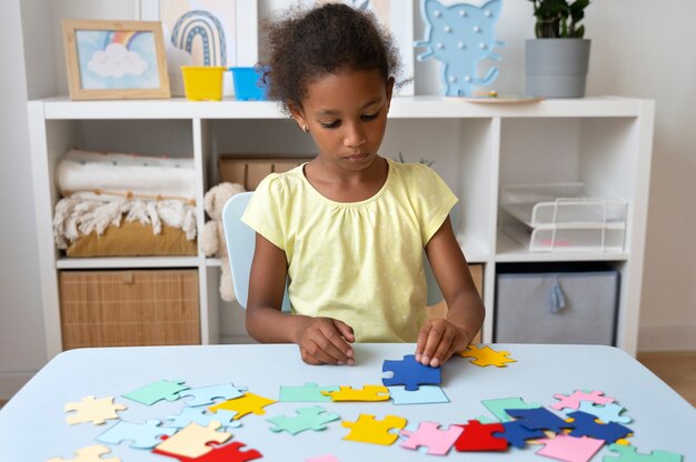 Front view girl making puzzle at table