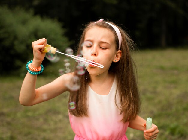 Front view of girl making soap bubbles