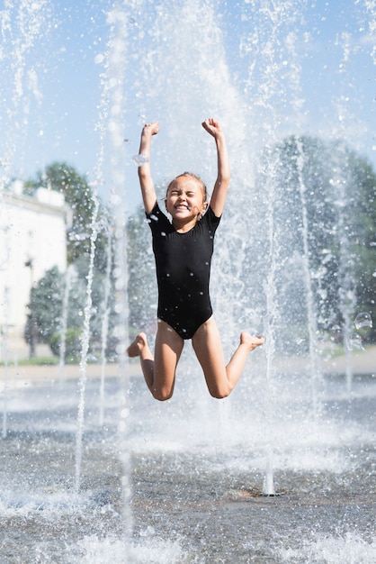 Free photo front view of girl playing at fountain